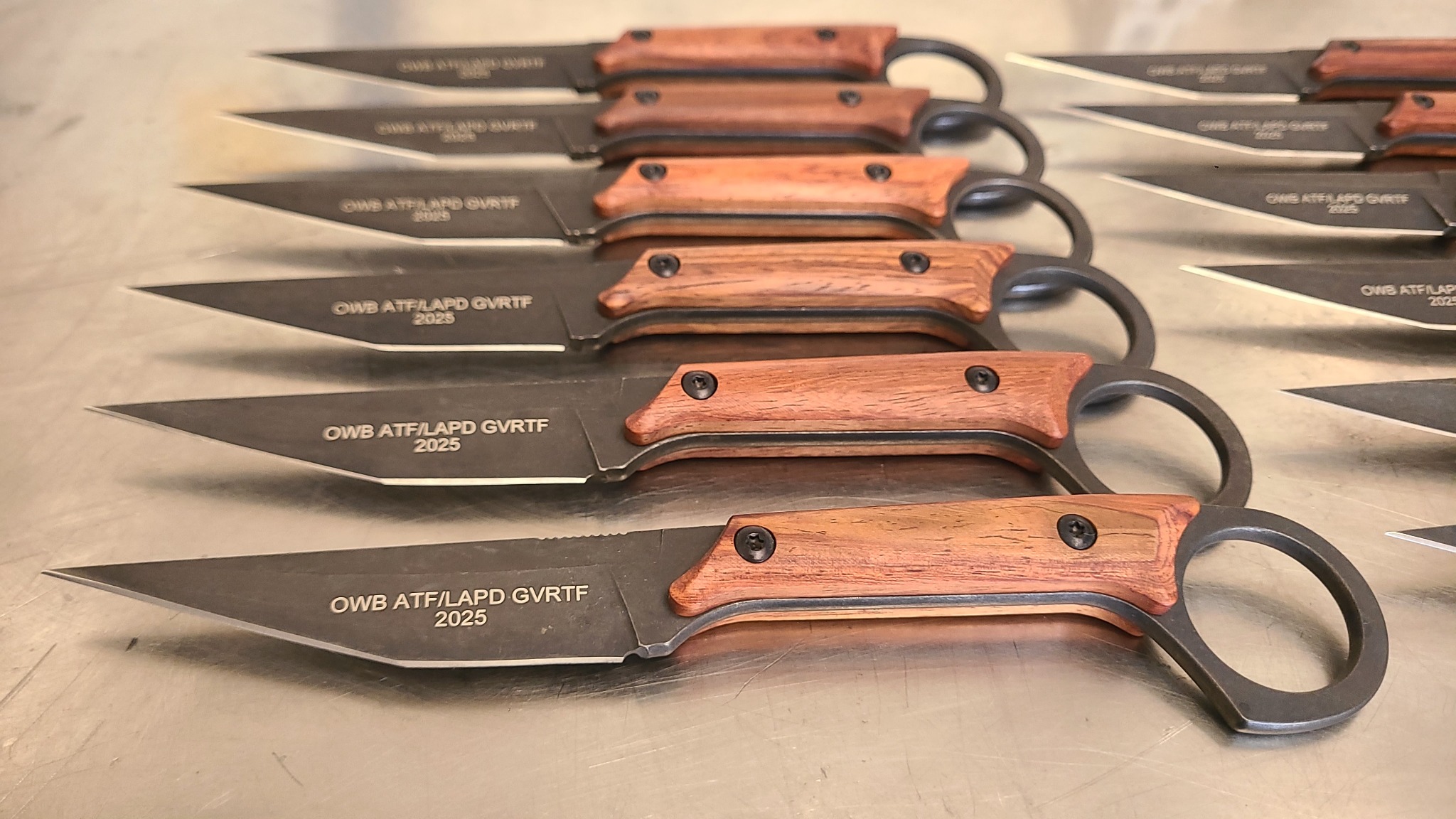 Matching text engraved across a batch of knife blades at LA LASER 1 in Valencia