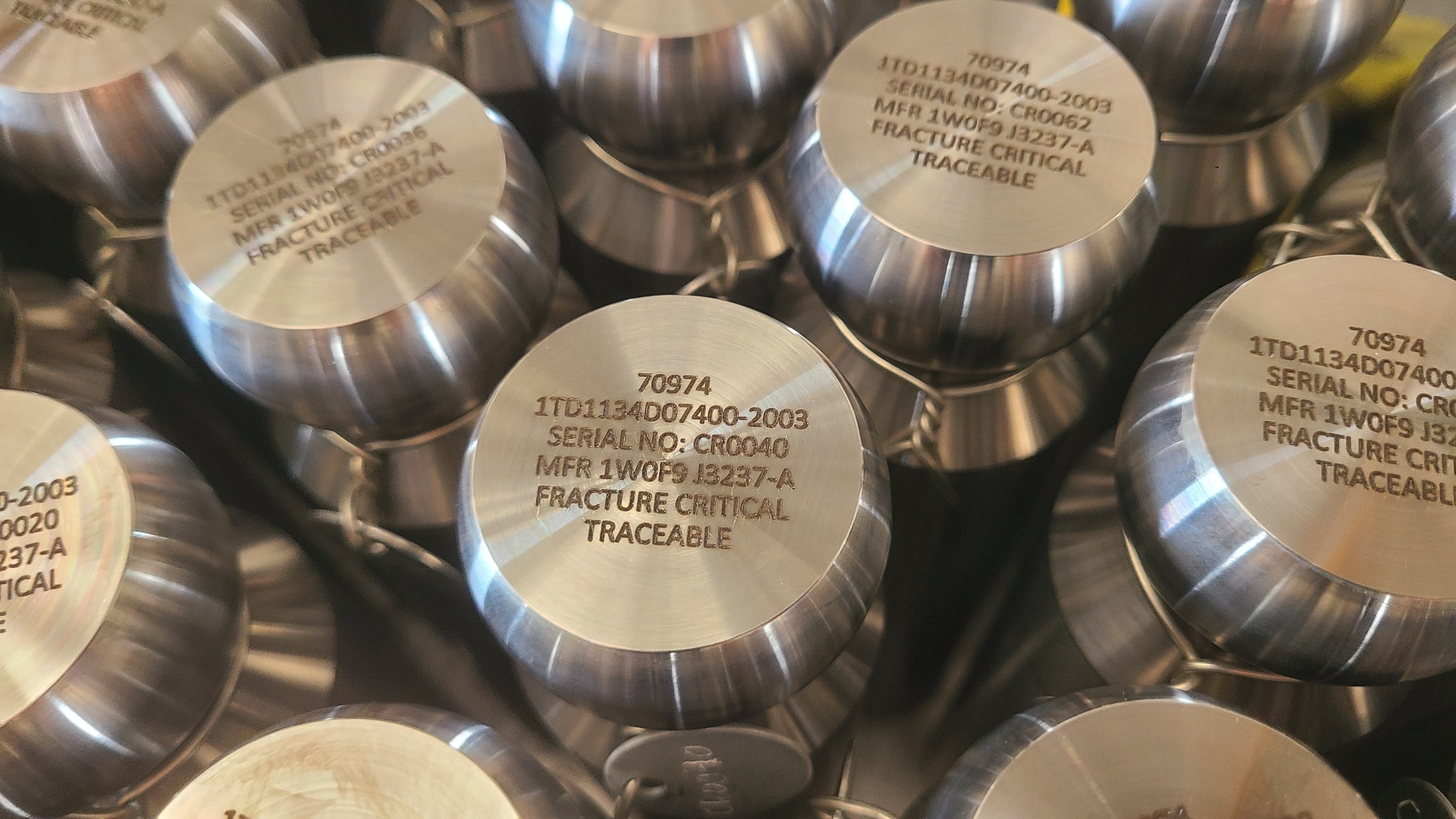 Close-up of part and serial-number markings on machined metal components at LA LASER 1